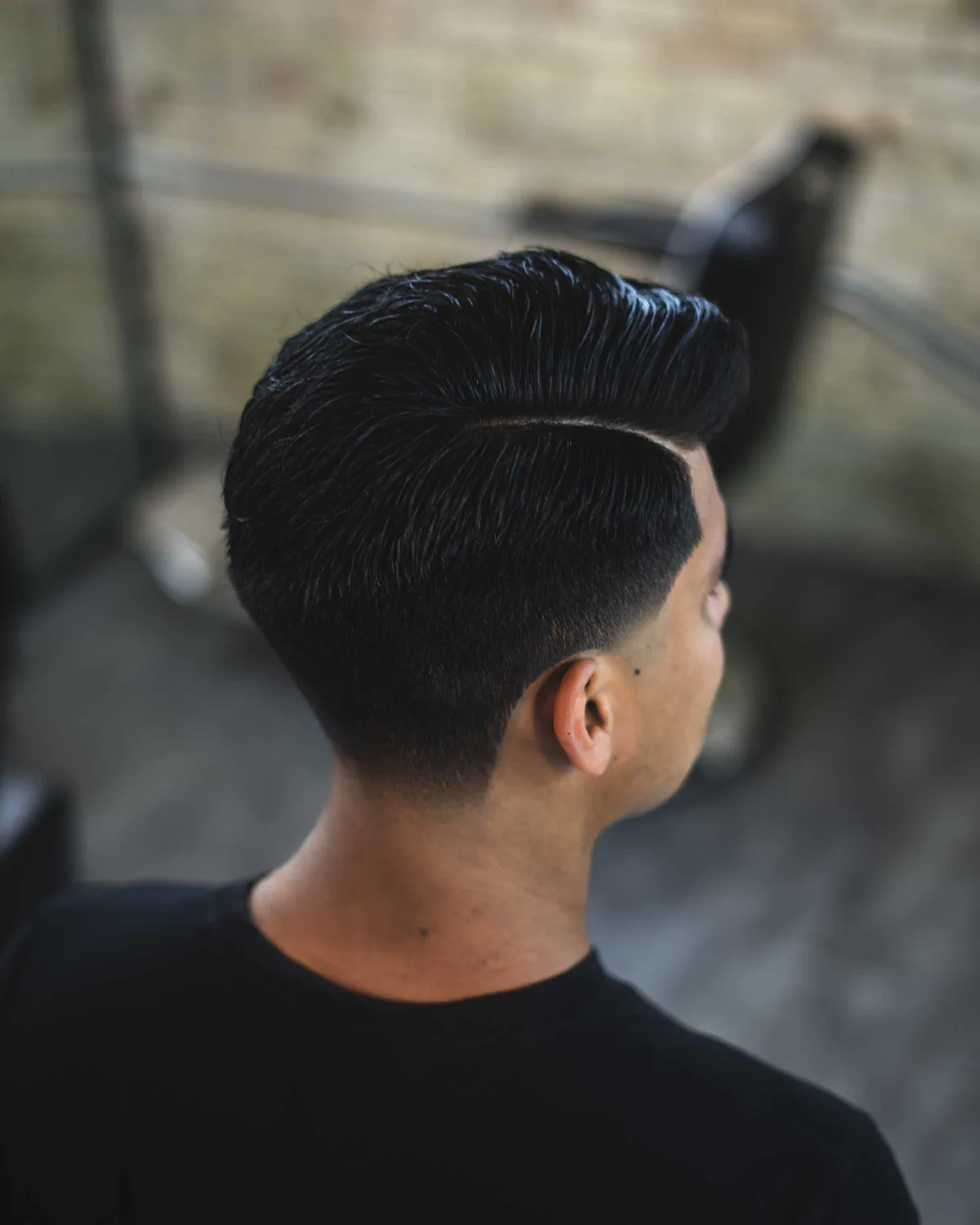 Slicked-back pompadour with a hard part and a tapered back, cut at Studio AZ Barbershop in the North Loop, Minneapolis