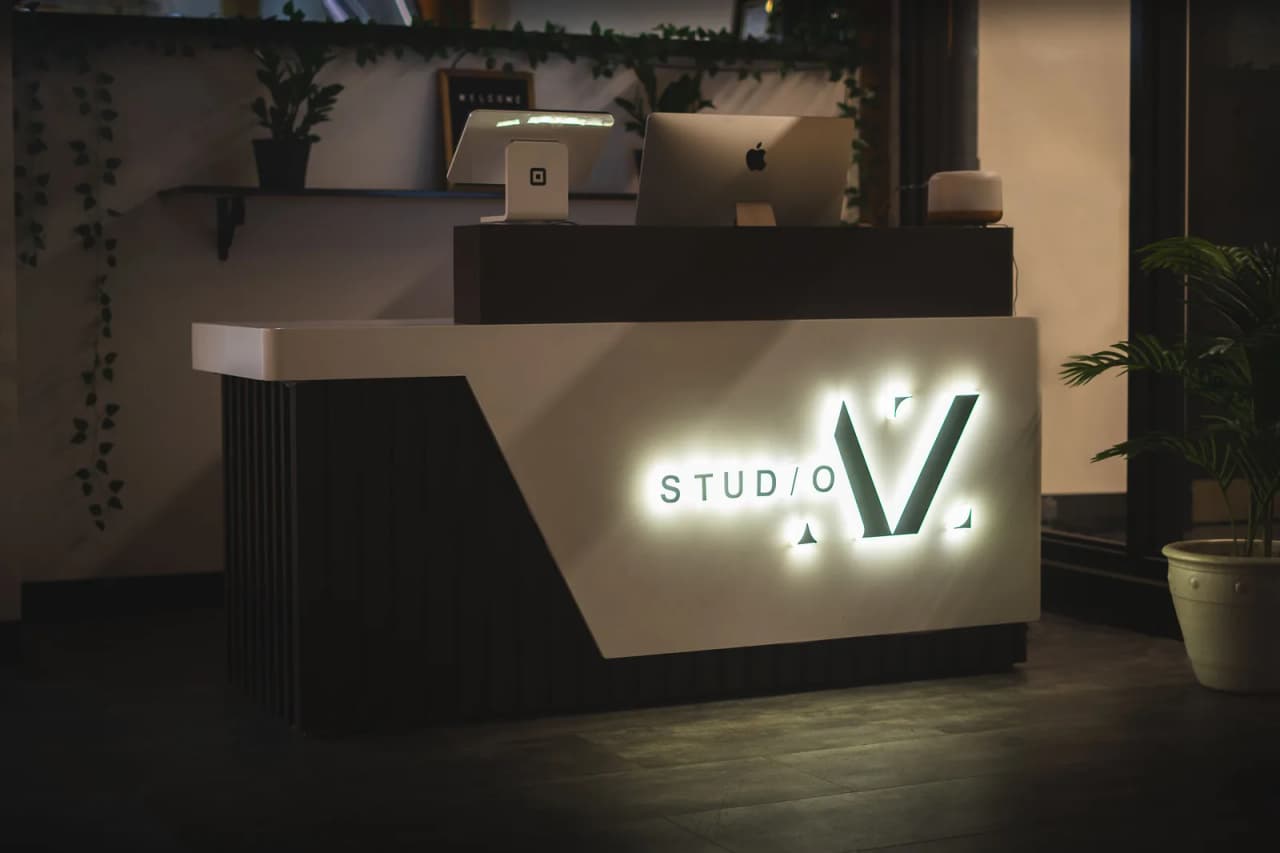 The front desk at Studio AZ, with the backlit Studio AZ sign, shared by the barbershop and the tattoo studio downstairs