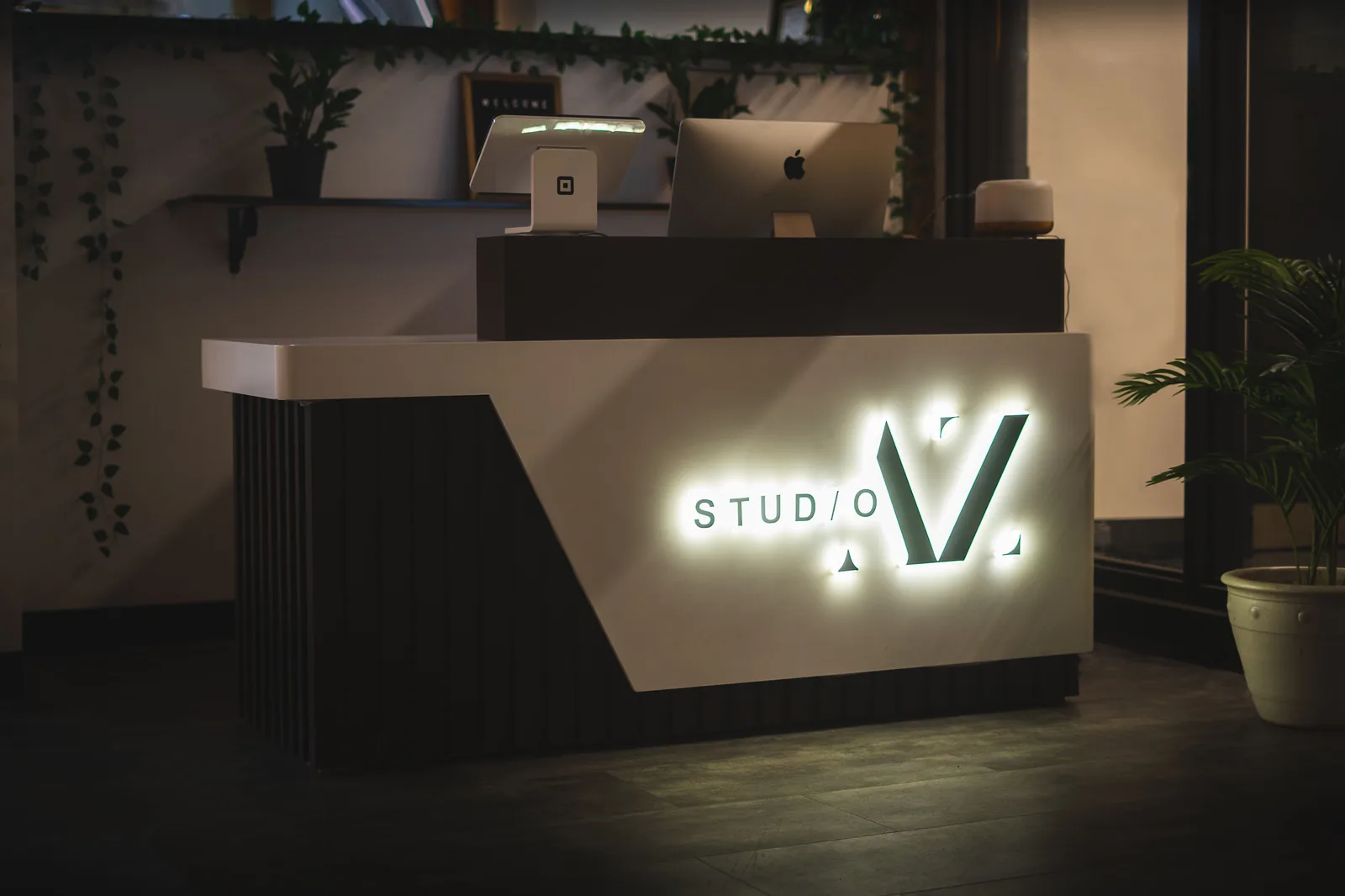 The front desk at Studio AZ, with the backlit Studio AZ sign, shared by the barbershop and the tattoo studio downstairs