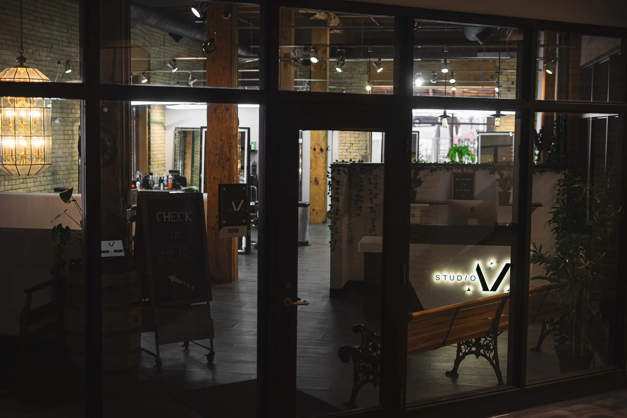 Studio AZ Barbershop at night, seen from the sidewalk through the glass storefront of Union Plaza in the Minneapolis North Loop