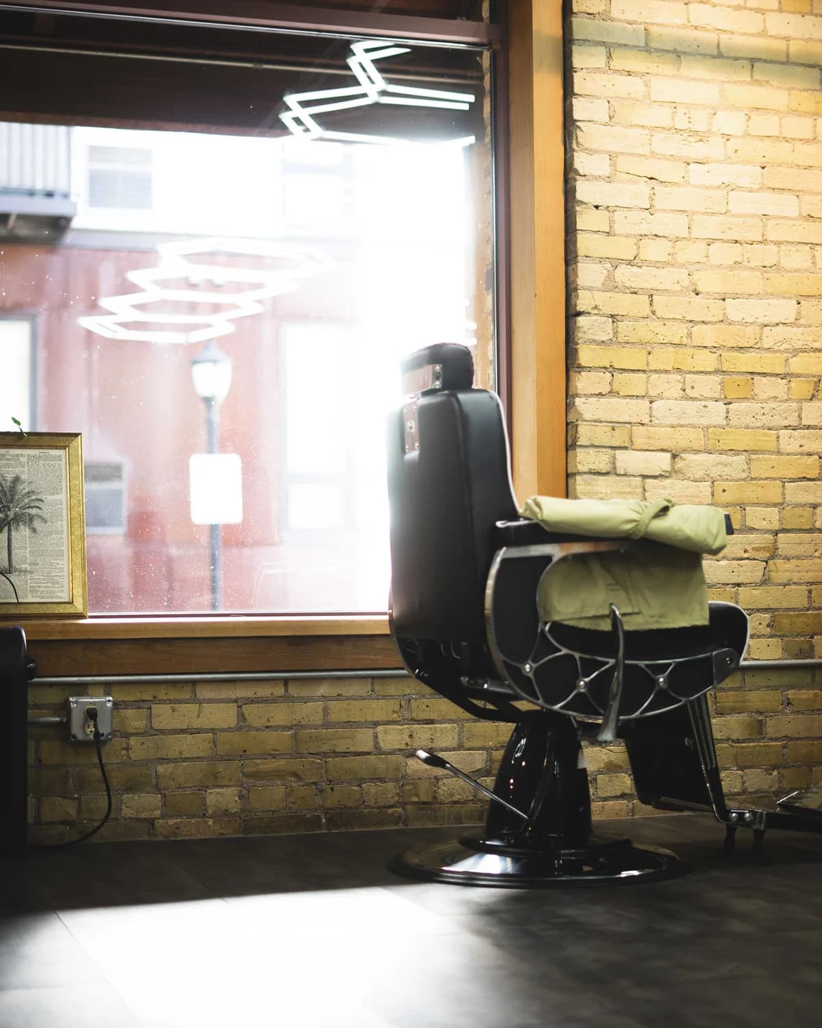 Vintage barber chair beside a window and exposed brick wall at Studio AZ Barbershop in the Minneapolis North Loop